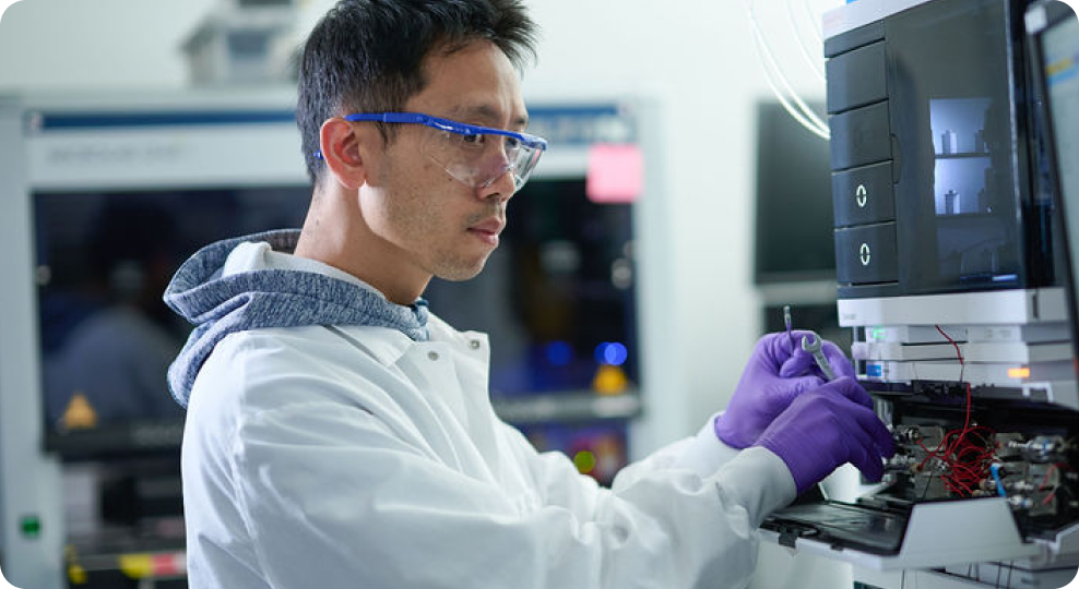 Scientist in lab coat and gloves working with laboratory equipment.
