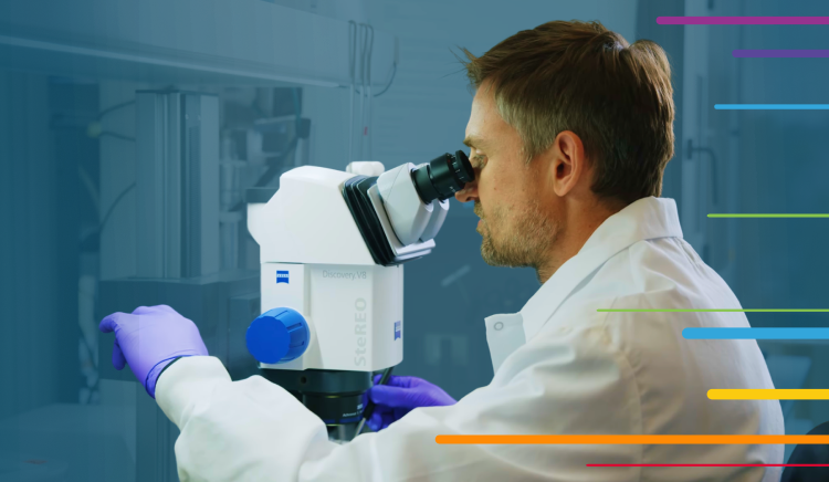 Scientist wearing gloves looks through a microscope in a laboratory.