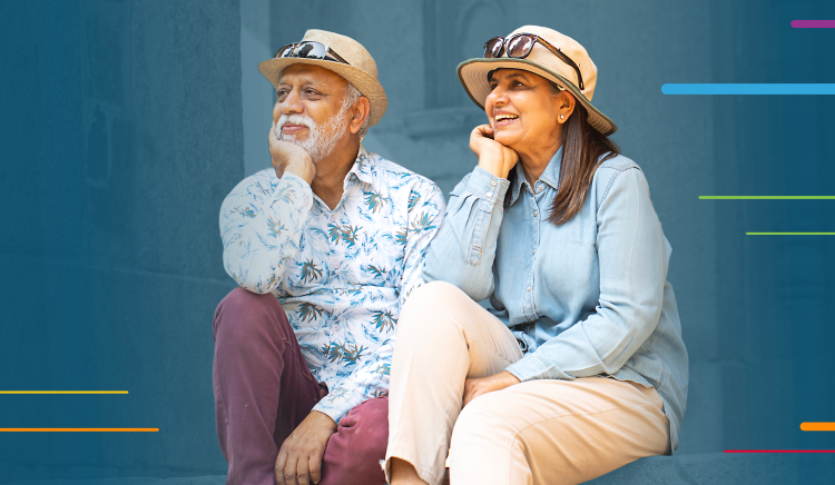 Smiling elderly couple sitting together, both wearing hats and casual clothes.