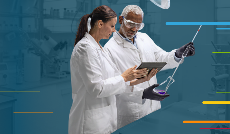 Two scientists in lab coats reviewing data on a tablet in a laboratory.