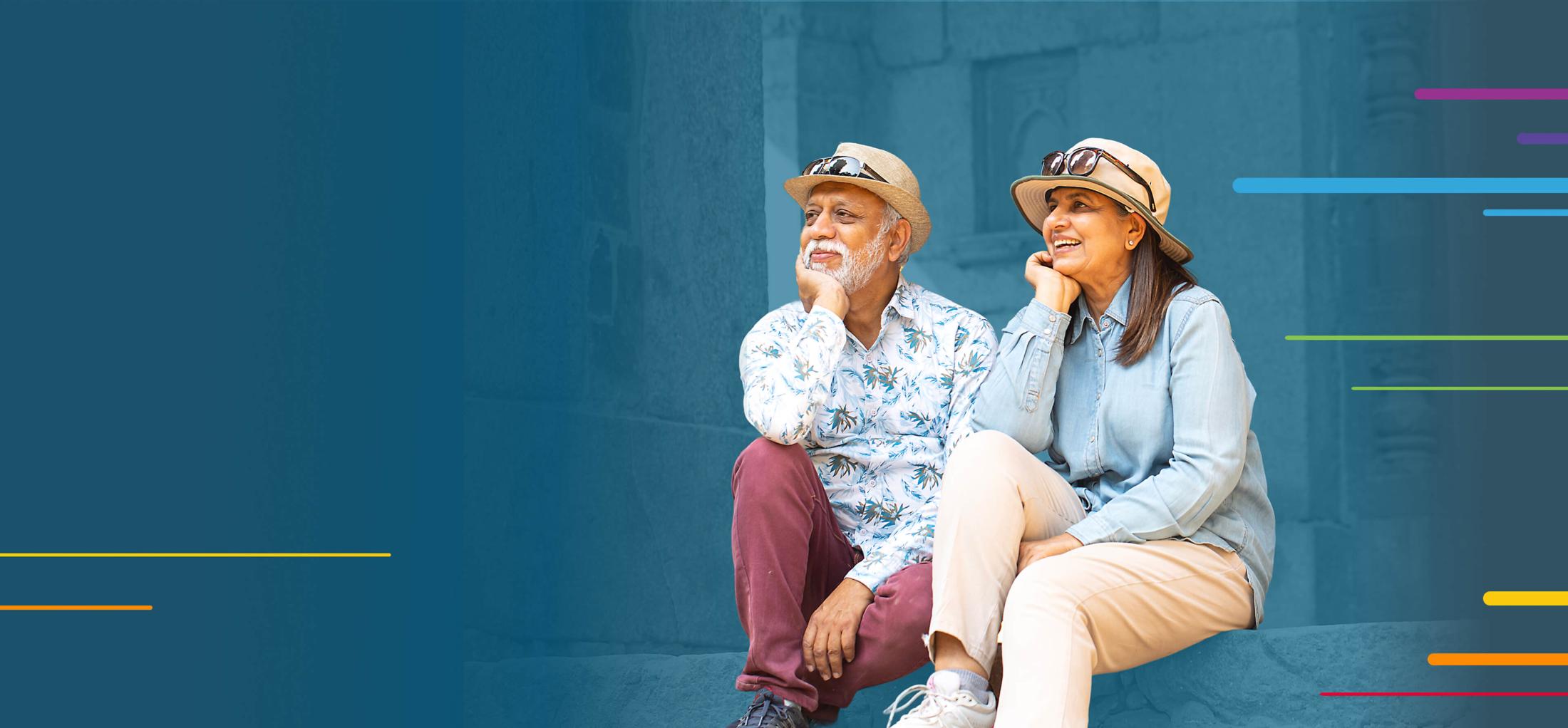 Smiling elderly couple sitting together, both wearing hats and casual clothes.