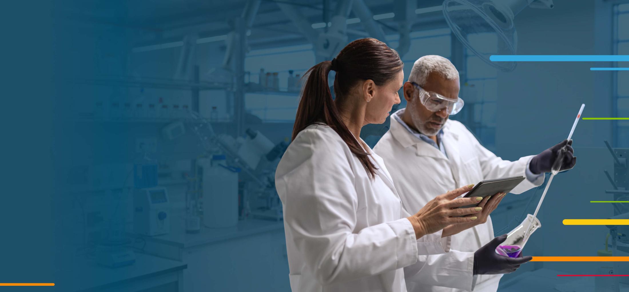 Two scientists in lab coats reviewing data on a tablet in a laboratory.